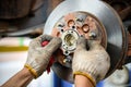 car repair service Mechanic is putting lubricating grease into bearings and assembling new car bearings. Car mechanic inspecting