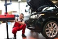 Car repair shop - worker checks and adjusts the headlights of a