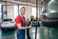 Car repairer with hose near car in garage Royalty Free Stock Photo