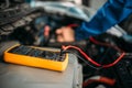 Car repairman with multimeter, battery inspection Royalty Free Stock Photo
