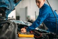 Car repairman with multimeter, battery inspection