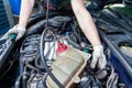 A car repairman unscrews parts with a wrench with a green handle in the engine compartment suh as spark plugs and ignition coils