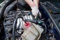 A car repairman unscrews parts with a wrench with a green handle in the engine compartment suh as spark plugs and ignition coils