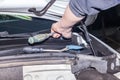 A car repairman unscrews parts with a wrench with a green handle in the engine compartment in a vehicle repair Royalty Free Stock Photo