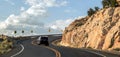 Car riding on a curvy road hairpin turn on a high terrace around a mountain with a scenic blue sky panorama