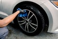 Car rims cleaning, car detailing wash concept. Cropped close up photo of male hand in black rubber glove with blue