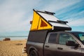 Car roof tent for camping. Car on parking lot close to the beach with light camper car tent on a roof Royalty Free Stock Photo