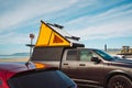 Car roof tent for camping. Car on parking lot close to the beach with light camper car tent on a roof Royalty Free Stock Photo