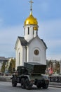 Car of Russian army against background of white chapel. Military equipment drives through the empty streets of city.