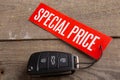 Car sale concept. Special price! Vehicle security key with tag on the wooden background