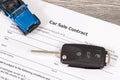 Car sale contract, blue toy car and black key. Sales, purchases of vehicle Royalty Free Stock Photo