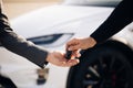 Car Salesman Finishing Up Dealing Car. Young Happy Man Receiving Car Keys to Her New Automobile. Dealer giving key to Royalty Free Stock Photo