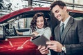 Car salesman giving explanations on tablet to pretty young woman Royalty Free Stock Photo