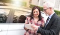 Car salesman giving explanations on tablet to young woman, light effect Royalty Free Stock Photo