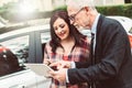 Car salesman giving explanations on tablet to young woman, light effect Royalty Free Stock Photo