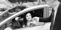 Car salesman giving car keys to young woman, geometric pattern Royalty Free Stock Photo