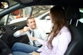 car salesman hands over the car key in the car dealership to customers