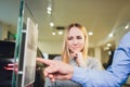 Car salesman helps woman client to choose a new car in the dealership.