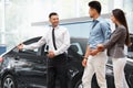 Car Salesman Invites Customers at Showroom. Royalty Free Stock Photo