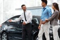 Car Salesman Invites Customers at Showroom. Royalty Free Stock Photo