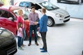 Car salesman showing new vehicle to customers