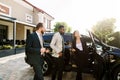 Car salon, sale and rent concept. African and Caucasian men in business wear buying the car. Elegant woman car Royalty Free Stock Photo