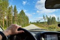Car salon, steering wheel, hand of woman and view on nature landscape. Road, forest, blue sky, white clouds at sunny day. Concept Royalty Free Stock Photo