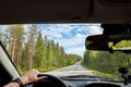 Car salon, steering wheel, hand of woman and view on nature landscape. Road, forest, blue sky, white clouds at sunny day. Concept Royalty Free Stock Photo