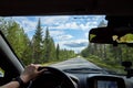 Car salon, steering wheel, hand of woman and view on nature landscape. Road, forest, blue sky, white clouds at sunny day. Concept Royalty Free Stock Photo