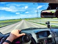 Car salon, steering wheel, hand of woman and view on nature landscape. View from seat of driver on Road, forest, blue