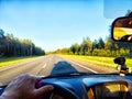 Car salon, steering wheel, hand of woman and view on nature landscape. View from seat of driver on Road, forest, blue