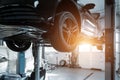 Car service center. Bottom behind pov vehicle raised on lift technician worker perform diagnosticas and inspection at