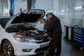 In a car service center good looking woman in a business suit her going to the car to check the problem in a auto garage