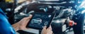Car service concept with mechanic using tablet for vehicle diagnostics and repair Royalty Free Stock Photo