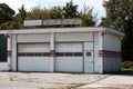 Car service garage abandoned by owners after going out of business with broken neon signs on top and dilapidated facade surrounded