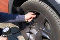 Car service. Male hand checks pressure in car tires. Auto maintenance concept