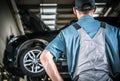 Car Service Mechanic in Front of Lifted Vehicle