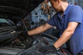 Car service, repair, maintenance and people concept - auto mechanic looking for a malfunction in the car engine Royalty Free Stock Photo