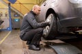 Auto mechanic changing car tire at workshop Royalty Free Stock Photo