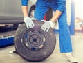 Mechanic with wheel tire at car workshop Royalty Free Stock Photo