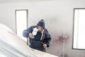 Car service station. Worker painting a white car in special garage, wearing costume and protective gear Royalty Free Stock Photo