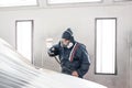 Car service station. Worker painting a white car in special garage, wearing costume and protective gear Royalty Free Stock Photo