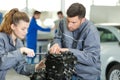 Car service technician and apprentice repairing engine