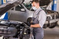 Car service worker carries out diagnostics and car repairs in the room