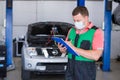 Car service worker carries out diagnostics and car repairs in the room