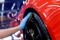 Car service worker polishing car wheels with microfiber cloth.