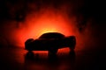 The car in the shadows with glowing lights in low light, or silhouette of sport car dark background