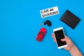 Car sharing app concept. Toy car, car key, auto drive license, human hand with smartphone and text sign Royalty Free Stock Photo