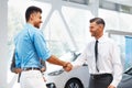 Car Showroom. Young Couple is Meeting with Seller in Auto Salon