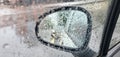 Car side glass view in raining with rain drops on it. Bokeh on rear view mirror car moving amid rain concept Royalty Free Stock Photo